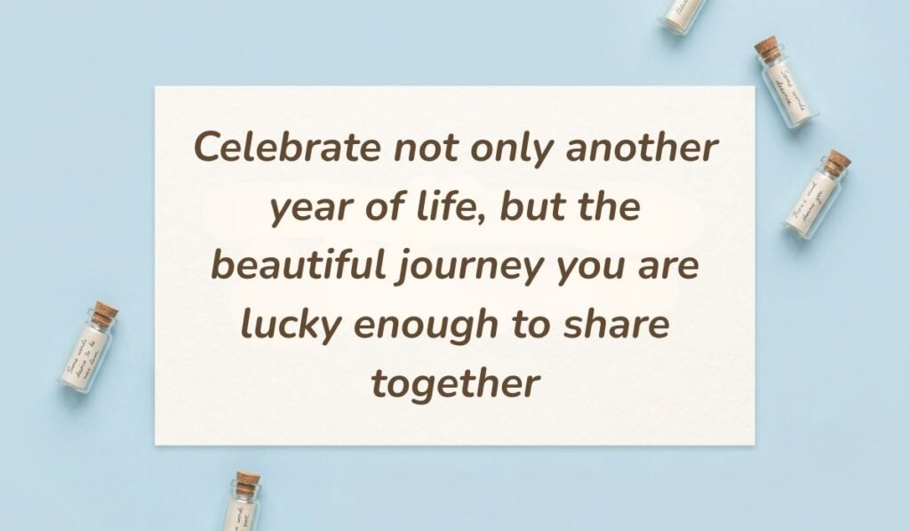 Soft blue background styled with small glass message bottles featuring birthday wishes for twins reading "Celebrate not only another year of life, but the beautiful journey you are lucky enough to share together"
