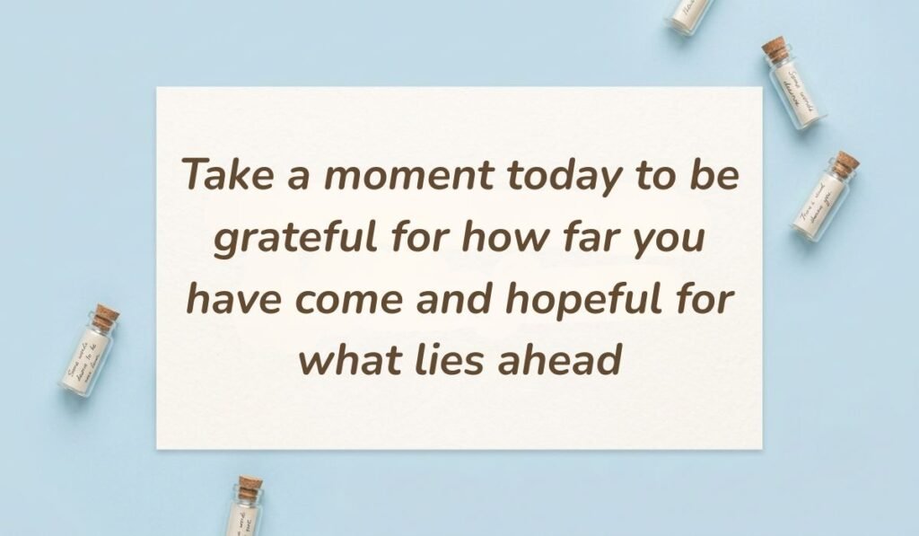 Soft blue flatlay background decorated with tiny message bottles presenting happy friday blessings and messages reading "Take a moment today to be grateful for how far you have come and hopeful for what lies ahead"